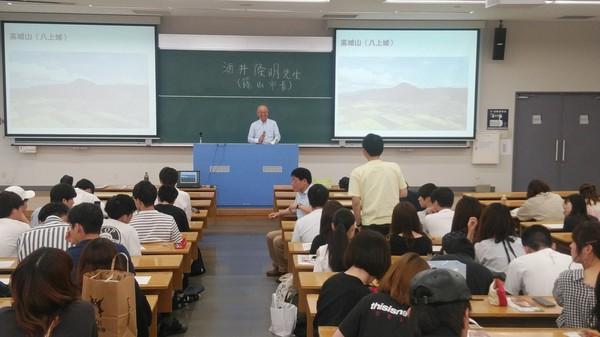 スクリーンを両側に講義をしている篠山市長とそれを真剣に聞いている生徒たちの写真